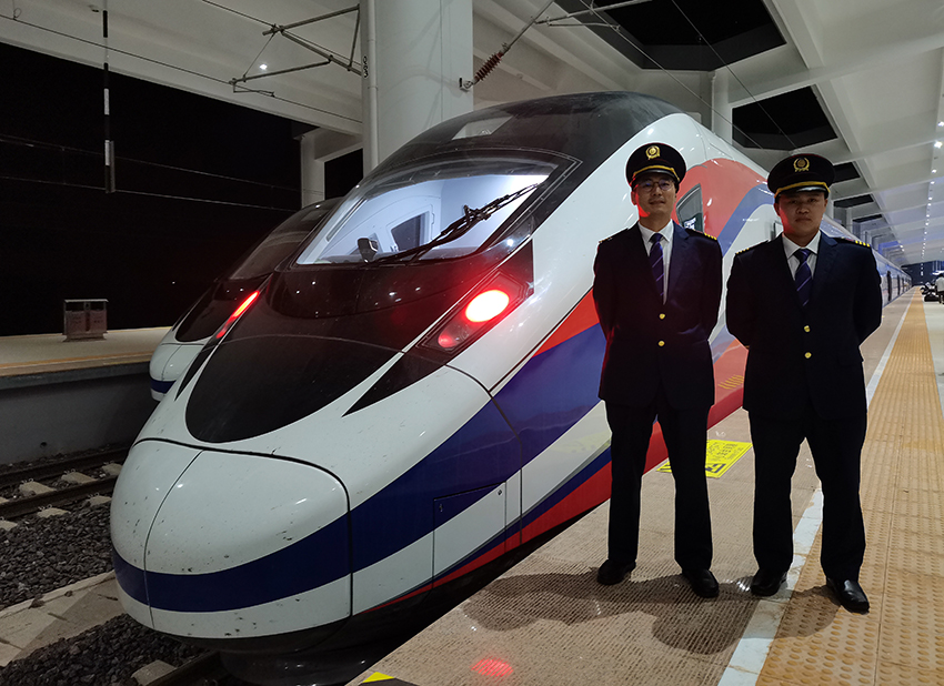 劉銀能（右一）與中國師父鄔俊鴻在動車組前合影。受訪者供圖